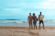 © shintartanya - company of young guys Sri Lankans, Indians surfers on the ocean coast with a surfboard, sporty tanned body, smiling and running with a surfboard on the beach on a sunny summer day, ready to surf.