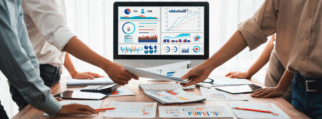 Leinwandbilder - Analyst team utilizing BI Fintech to analyze and pointing at financial dashboard paper office. Businesspeople examining report paper on table for business insight. Panorama shot. Scrutinize