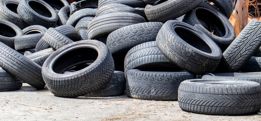 Industrial dump for the processing of used tires and rubber tires. Pile of old tires and wheels for rubber recycling. Tire dump. Recycling of used tires. Produced reclaimed tire rubber.