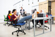 © Nikola Spasenoski - Group of multiethnic colleagues working on desktop computers in a modern office space. Girl resting with feet on table