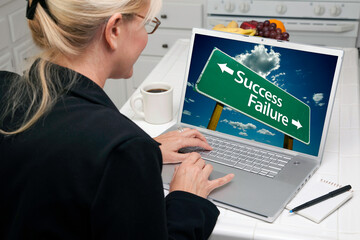 Woman In Kitchen Using Laptop with Success or Failure Road Sign on Screen. Screen can be easily used for your own message or picture. Picture on screen is my copyright as well.