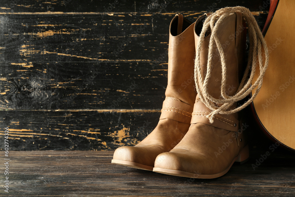 Cowboy boots, guitar and lasso on wooden background
