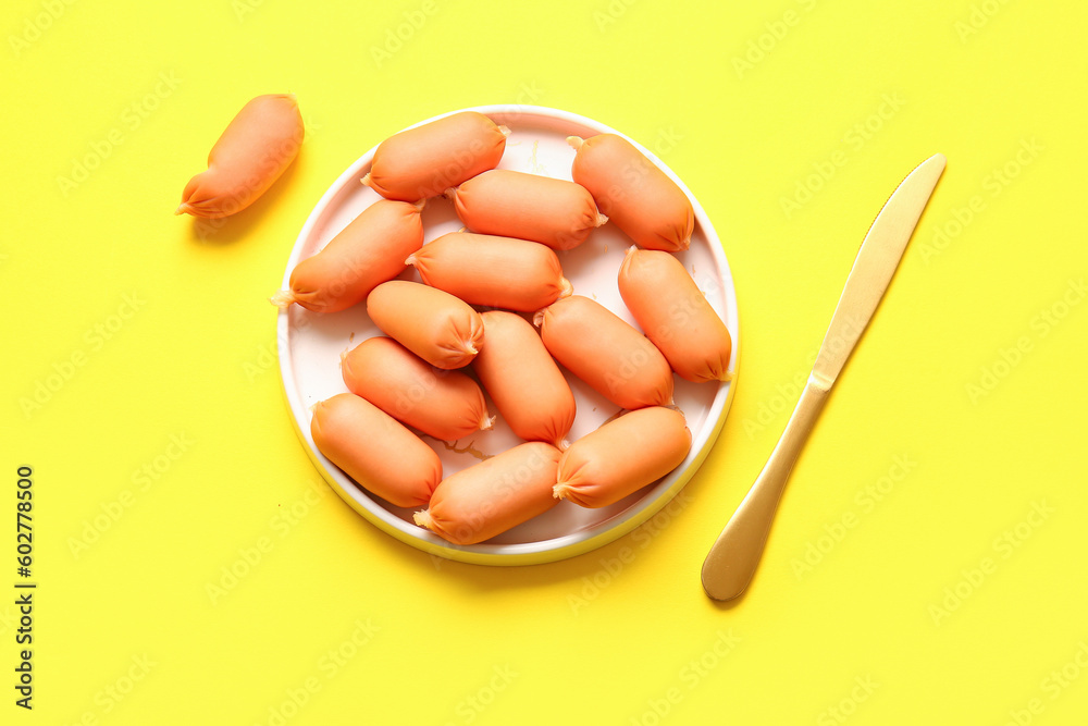 Plate of tasty boiled sausages on yellow background