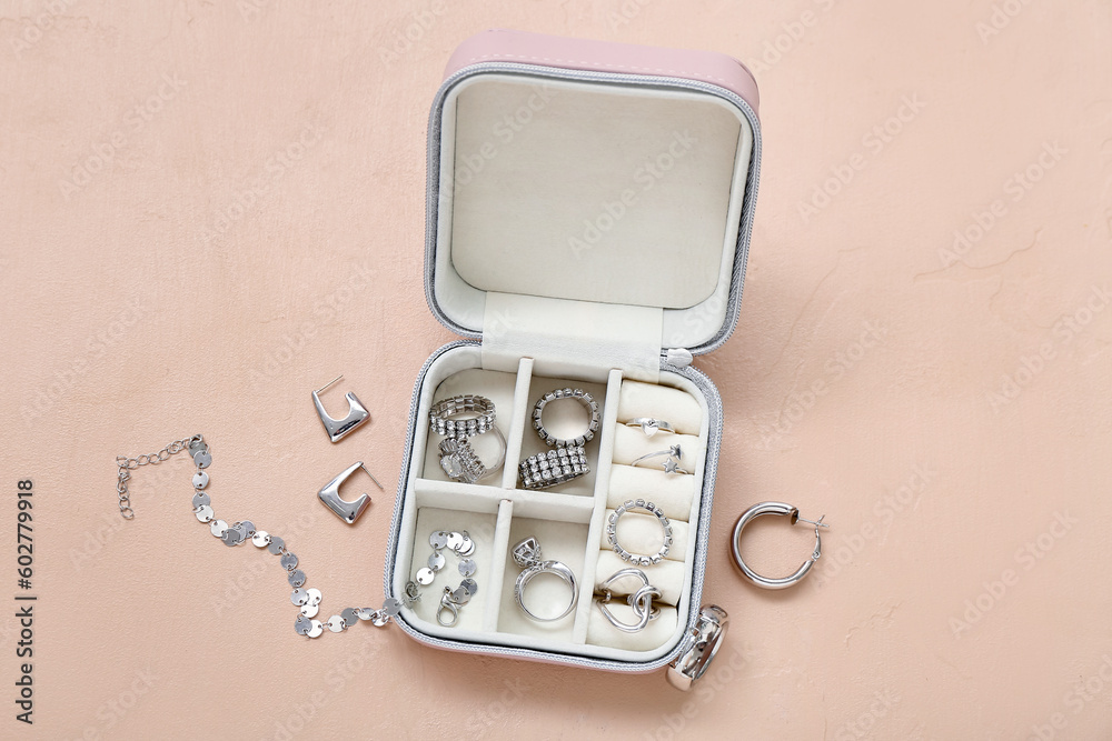 Organizer with stylish jewelry on pale orange background