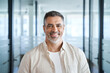 © Stock 4 You - Headshot close up portrait of indian or latin confident mature good looking middle age leader, ceo male businessman on blur office background. Handsome hispanic senior business man smiling at camera.
