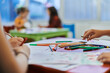 © .shock - Close up photo of kids during an art class in a daycare center or elementary school classroom drawing with female teacher.