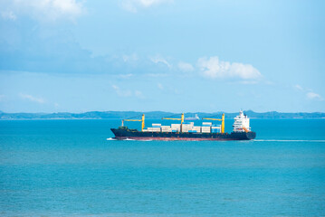 Cargo container ship sailing through peaceful, calm, blue sea on her voyage through the Singapore Strait. 