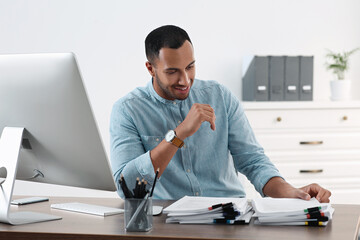 Wall Mural - Happy young businessman working with documents at wooden table in office