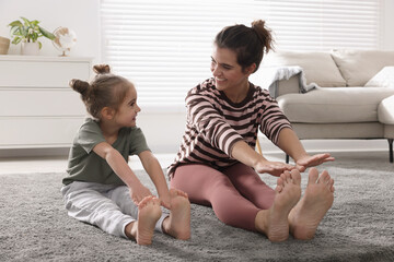 young mother and her daughter stretching together at home