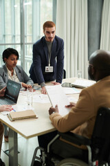 Aufkleber - focus on young businessman looking at male colleague in wheelchair while standing in front of him an