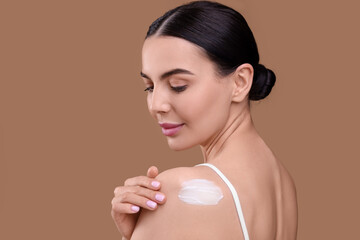 Canvas Print - Beautiful woman with smear of body cream on her shoulder against light brown background