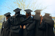 © Jadon B/peopleimages.com - Embrace, group of graduates and together with joy on graduation day or celebrating academic achievement and outdoors. Certification, young students and hug outside or robes or hats and education
