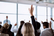 © Nikish H/peopleimages.com - Conference, crowd and business people with hands for a question, vote or volunteering. Corporate event, meeting and hand raised in a training seminar for questions, voting or audience opinion