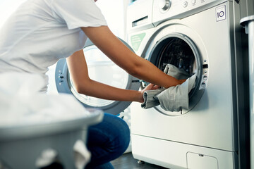 Closeup, cleaning and woman with laundry, machine and home with clothes, fabric and housekeeping. Zoom, female person and cleaner washing items, housework and laundromat with routine and service