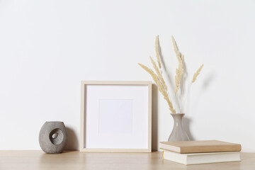 Canvas Print - Empty photo frame and vase with dry decorative spikes on wooden table. Mockup for design