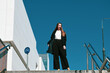 The white beatiful girl shows her black coat against the blue sky
