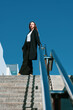 The white beatiful girl hold the handrail against the blue sky