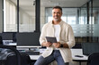 © Stock 4 You - Latin Hispanic mature adult professional business man looking at camera and smiling. Indian senior businessman holding digital tablet using fintech application sitting at table in casual pose office.