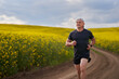 © Xalanx - Distance runner running on a road through canola field
