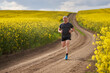 © Xalanx - Distance runner running on a road through canola field