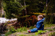 © Oleksii Yemelianov - Little toddler boy in blue spring warm outfit sitting on stone in forest
