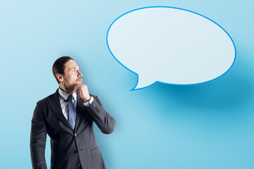 Aufkleber - Attractive young european businessman with speech bubble on blue background. Opinion, speech and communication concept. Mock up place.