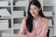 © Kritdanai - Cheerful business lady working on laptop in office, Asian happy beautiful businesswoman in formal suit work in workplace. Attractive female employee office worker smile.