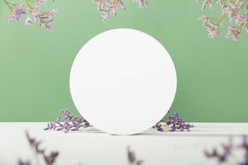 Abstract geometric pedestal and purple flowers on green background front view space for text