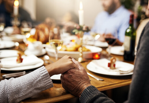 Closeup, thanksgiving and hand holding with family at table in dining room for holiday, food or worship. Celebration, support and gratitude with people praying at home for kindness, dinner and love