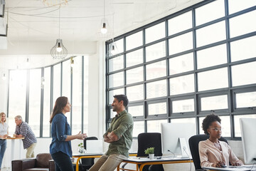 Conversation, man and woman in modern office with smile and creative advice at startup agency together. Talking, desk and happy team leader coaching designer at work with help, support and opinion.