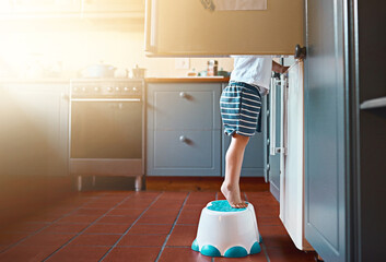 Wall Mural - Small, looking and a child on a step for refrigerator food, breakfast or a snack in a house. Kitchen, morning and a little kid standing on a chair to look for a meal or lunch in the fridge for hunger