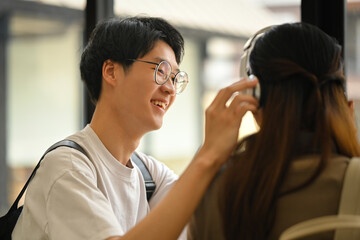 Happy moment of loving young asian man wearing headphones to his girlfriend. Lifestyle and love concept