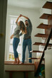 © A.S./peopleimages.com - Love, couple and dancing in home, bonding and having fun together for romance. Dance, happy and man and woman, funny and care, affection and enjoying quality time by stairs to relax on anniversary.