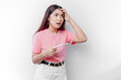 Unhappy woman wearing pink t-shirt looking at pregnancy test alone, confused young female shocked by result, bad news, covering open mouth with hand, unwanted pregnancy concept