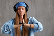 A young charming red-haired woman in a blue sweater and cap with DJ headphones on her head folded her hands in a prayer pose. Music and meditation.