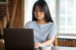 © zinkevych - Dark-haired young woman working on laptop and looking involved