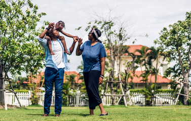 Wall Mural - Portrait of enjoy happy love black family african american father and mother with little african girl child smiling and play having fun moments good time in park at home