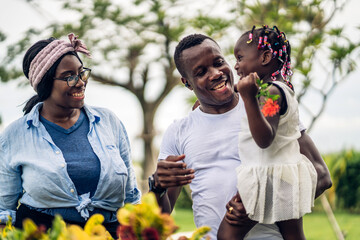 Wall Mural - Portrait of enjoy happy love black family african american father and mother with little african girl child smiling and play having fun moments good time in park at home