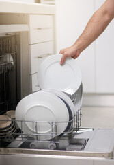 Cleaning, loading dishwasher and hands with plates in the kitchen for housework and responsibility. Lifestyle, morning and a person doing housekeeping, organizing crockery and clean equipment