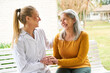 © Robert Kneschke - Senior woman talking with caregiver sitting in garden
