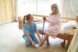 © Robert Kneschke - Caregiver helping elderly woman in putting slippers at rehab center