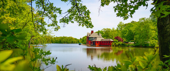 Wall Mural - Red boat house on the Roosevelt Lake at Roger Williams Park, Providence, Rhode Island, vibrant green spring colors in the forest