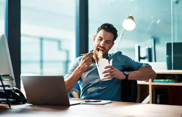 Wall Mural - Business, man and eating noodles in office at desk, laptop and working in startup company at night. Hungry young male employee, fast food and late dinner at computer technology in agency at evening