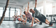 © Jadon B/peopleimages.com - Fitness class, group and people doing a workout in the gym for health, wellness and flexibility. Sports, training and athletes doing a side plank exercise challenge together in sport studio or center