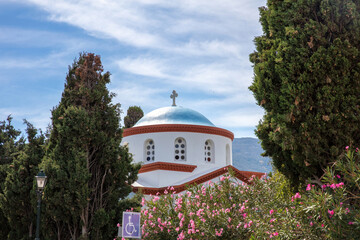 Wall Mural - Andros island, Chora town, Cyclades Greece. White orthodox church blue dome, view through tree.