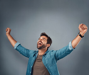 Wall Mural - Happy man, fist and celebration for winning, success or achievement against a grey studio background. Male person screaming in victory, win or accomplishment in motivation for goals on mockup space