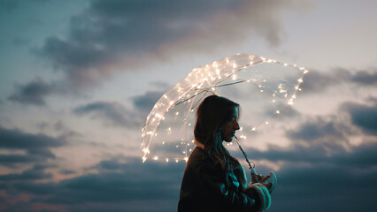 Wall Mural - Glowing umbrella of a girl walking on the beach in the night outdoor