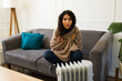 Latin woman shivering from the cold in front of the electric heater