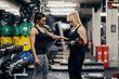 © dusanpetkovic1 - A female personal trainer is helping a female bodybuilder with exercises with barbell in a gym.