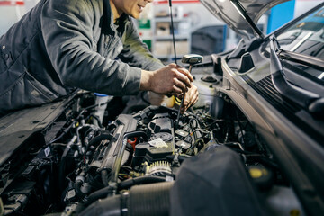 Wall Mural - Close up of a mechanic fixing car under the hood with tools at garage.